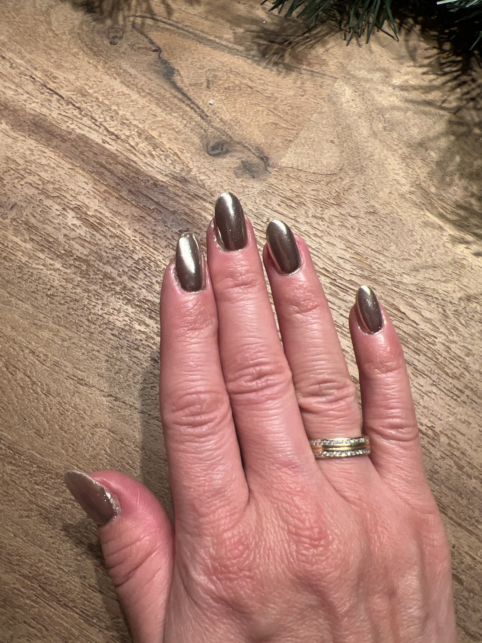 Hand met glanzende chroomnagels op een houten tafel