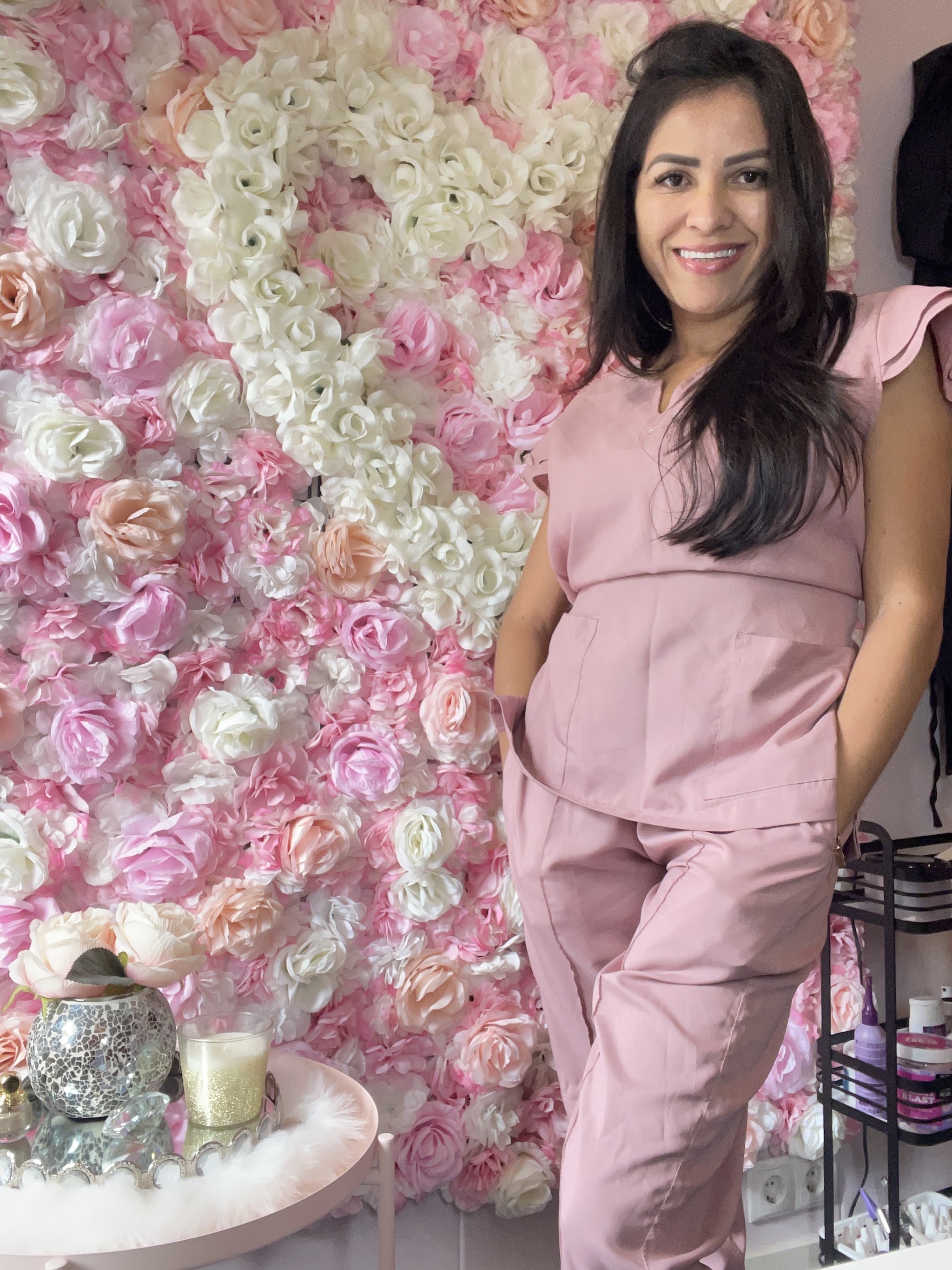 Germana Araújo in roze tenue voor de bloemenmuur in haar studio