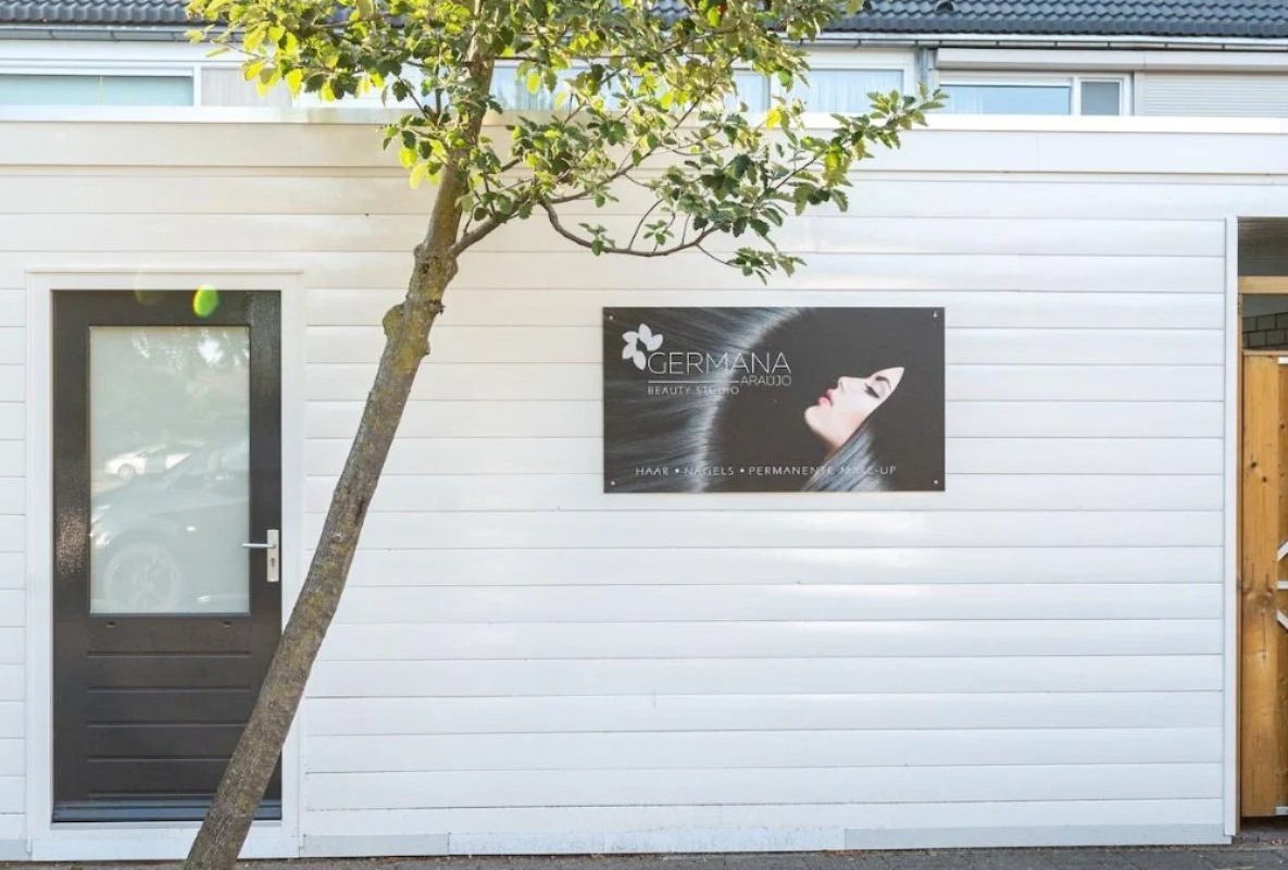 De witte studio met zwarte deur en het bord van Germana Araújo Beauty Studio
