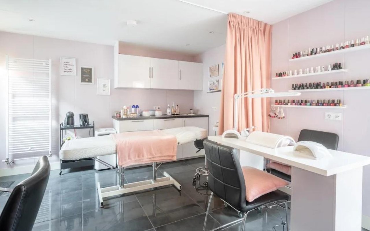 Behandelruimte met behandelbed, nageltafel en een rek met lakjes